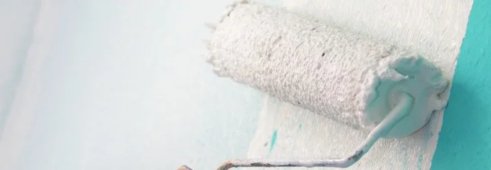 Hand streicht Wand mit Farbrolle weiß